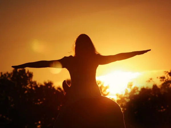 Angstfrei Reiten ist, wenn eine Frau mit ausgebreiteten Armen in den Sonnenuntergang reitet