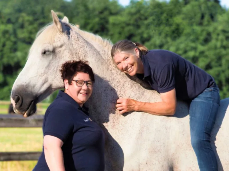 Angstfrei Reiten: Jutta Beckmann liegt auf dem PRE Schimmel Nino und Denise Beckmann steht davor.
