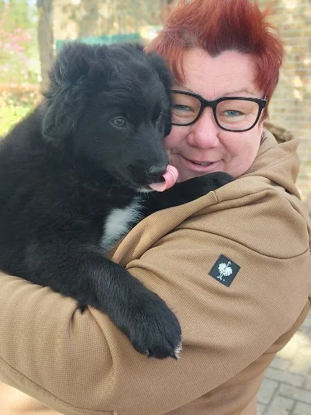 Eine Frau, die einen schwarzen Hund auf dem Arm hält.