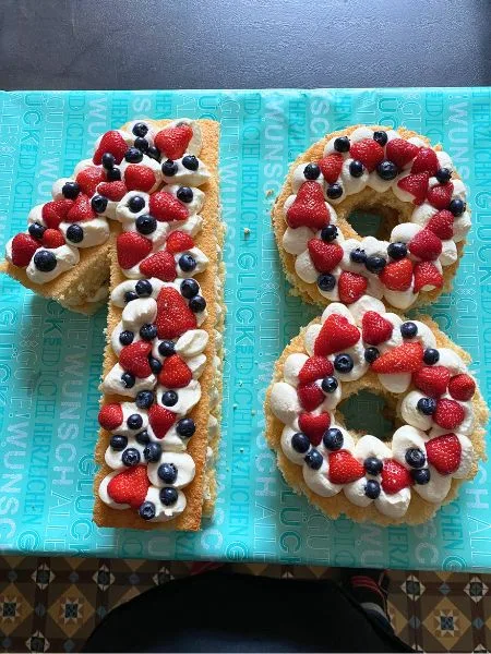 Ein Kuchen in Form von Zahlen mit Beeren obendrauf.