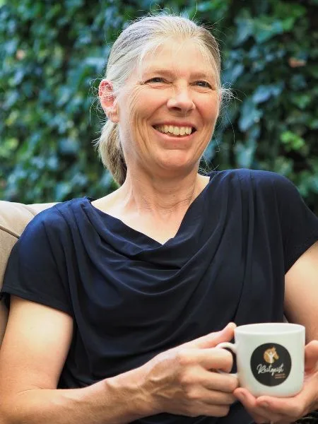 Eine Frau sitz mit Kaffeetasse im Gartensessel.