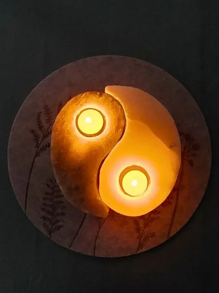 Zwei brennende Teelichter in Form von Yin und Yang.