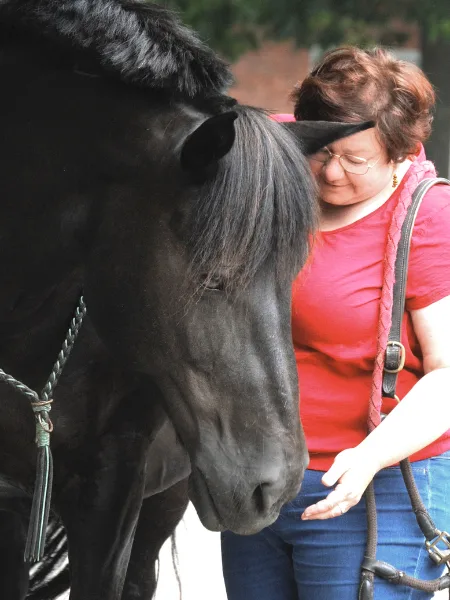 Bloggrafik Fairness: Eine Frau und ein Pferd mit Halsring in einem innigen Moment.