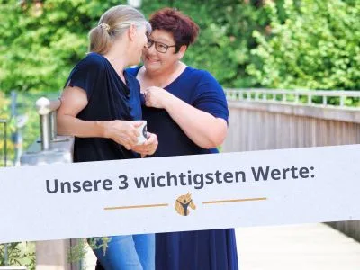 Bloggrafik: Unsere 3 wichtigsten Werte - Authentizität, Fairness und Zufriedenheit. Zwei Frauen stehen auf einer Brücke im grünen und albern herum.