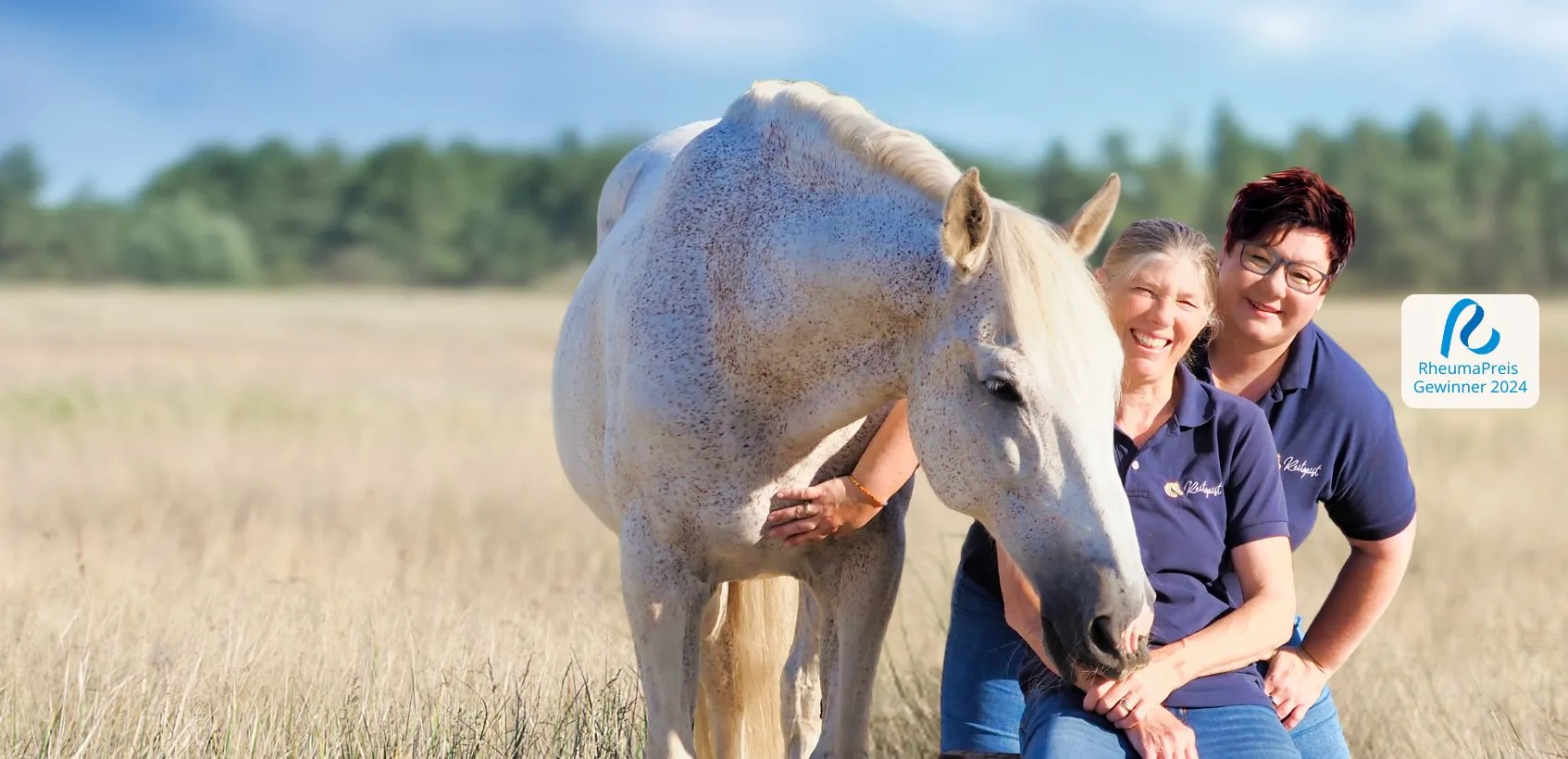 Zwei Frauen stehen mit Schimmel auf einem Kornfeld und schauen in die Kamera.