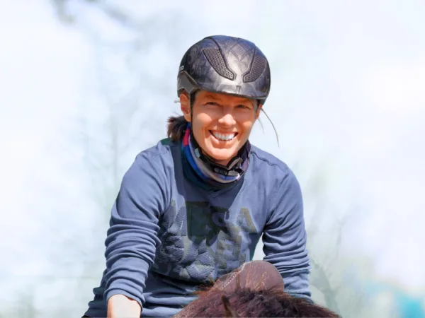 Angstfrei Reiten in einem Tag: Eine Frau sitzt mit breitem Grinsen auf einem Pferd.