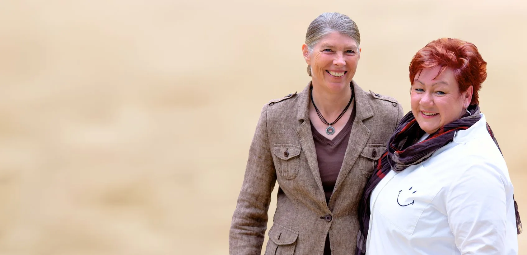 Jutta und Denise Beckmann - Reitgeist stehen Schulter an Schulter und schauen lächelnd in die Kamera.