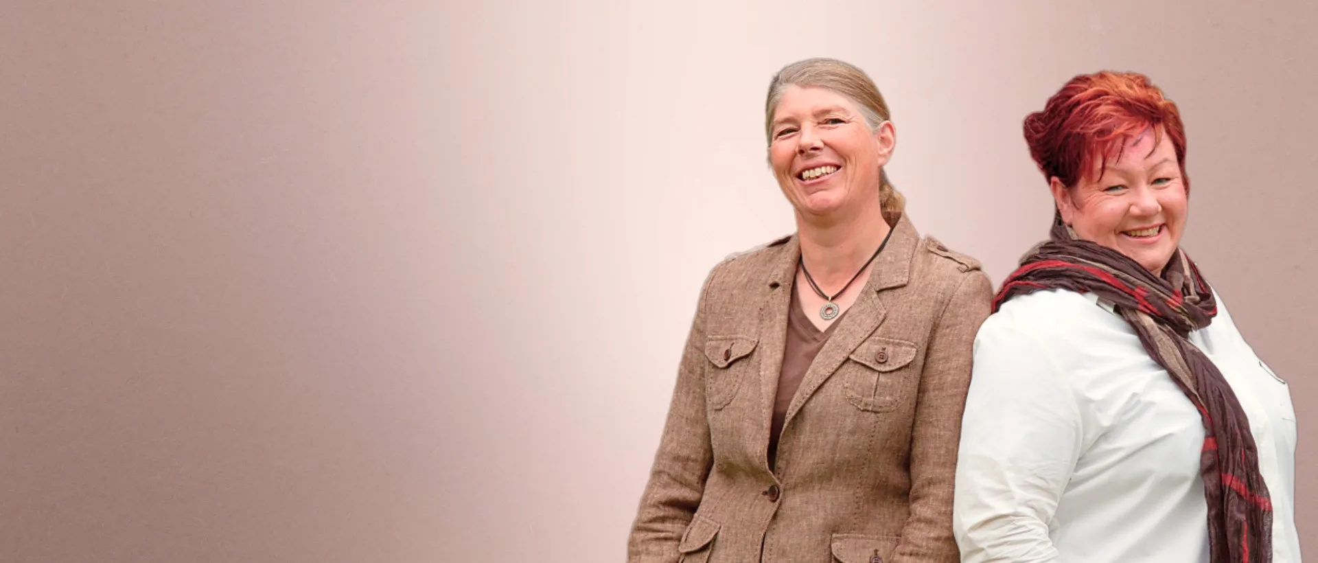 Jutta und Denise Beckmann stehen Rücken an Rücken, sind zur Kamera gewandt und schauen dich an.