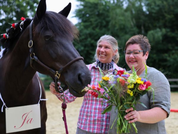 Jutta und Denise Beckmann beim Heiratsantrag mit Blumenstrauß neben ihrem Pferd.